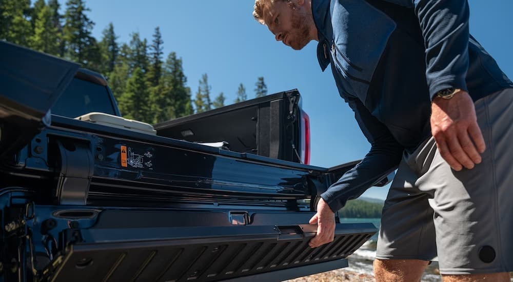 A person closing the tailgate on a black 2026 GMC Sierra 1500.