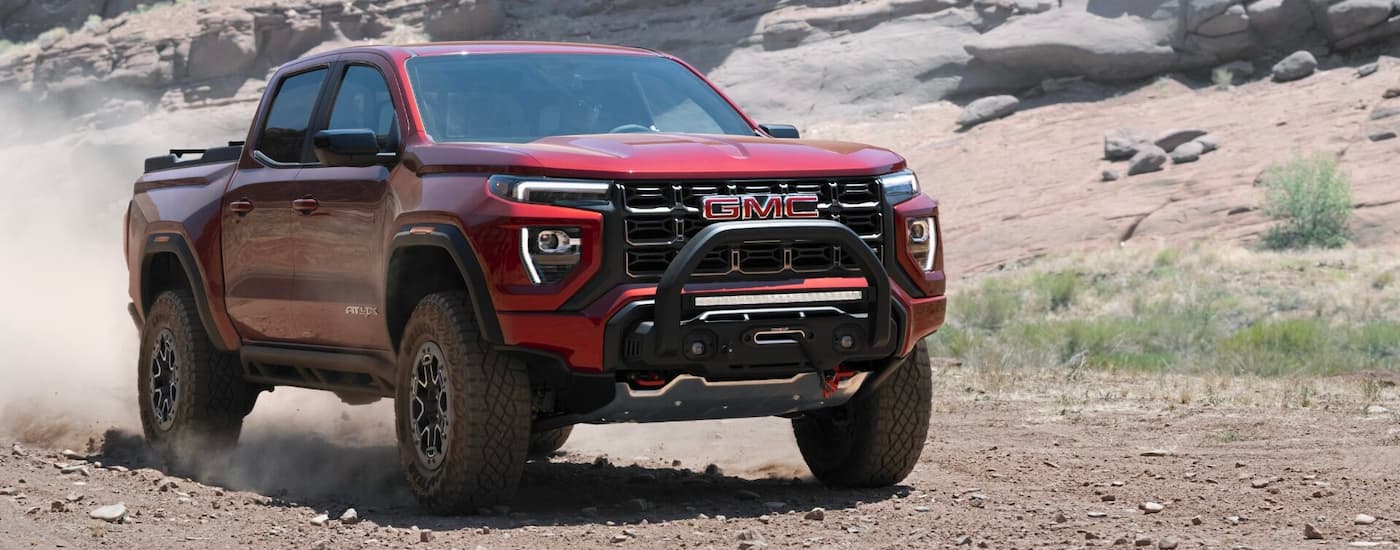 A red 2023 GMC Canyon AT4X driving a dirt road.