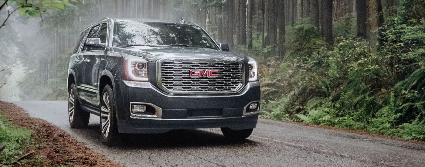 Black 2020 GMC Yukon driving down a road.
