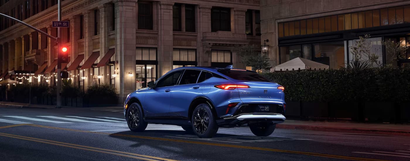 A blue 2026 Buick Envista driving down a city street at night