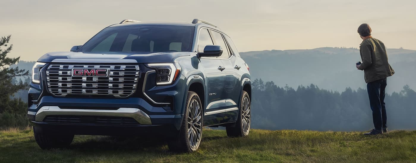 Blue 2026 GMC Terrain Denali parked off-road on a hill.
