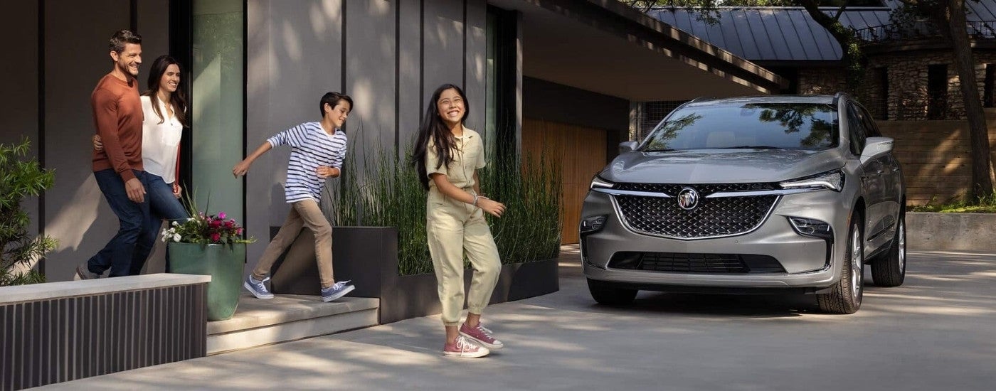 A family is approaching a grey 2024 Buick Enclave.