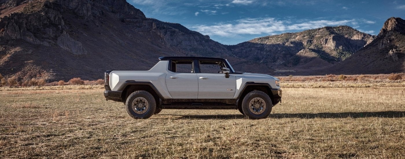 A white 2023 GMC Hummer EV is parked on dry grass after visiting a GMC dealer.
