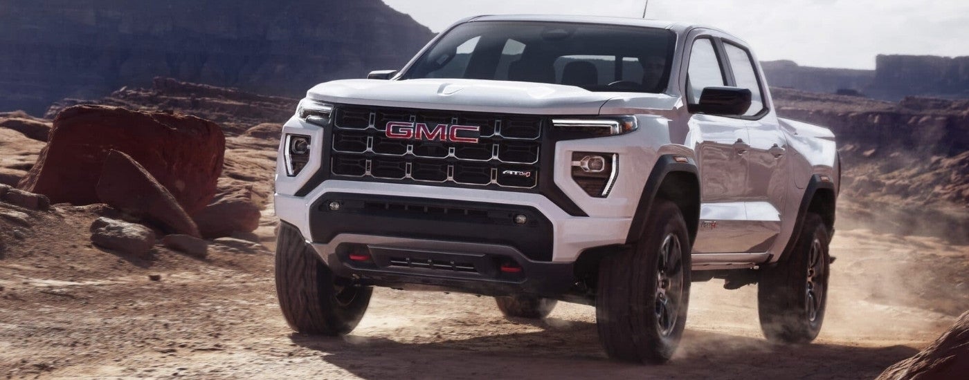 A white 2023 GMC Canyon AT4 is driving to a GMC dealer near Greenville.