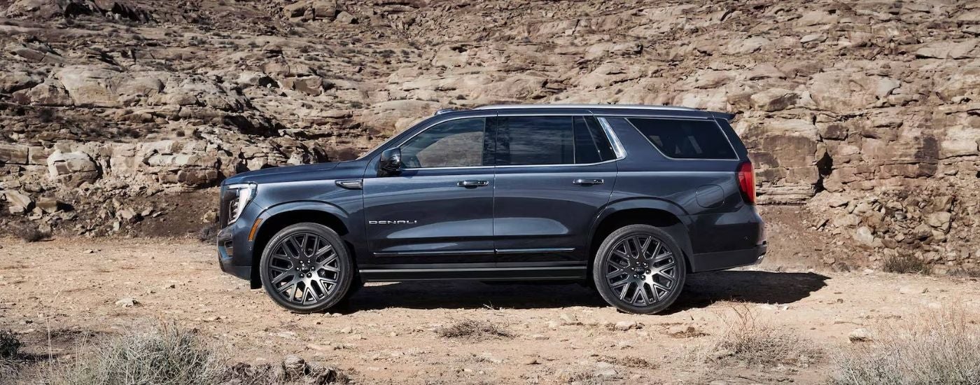 A grey 2025 GMC Yukon Denali parked off-road.
