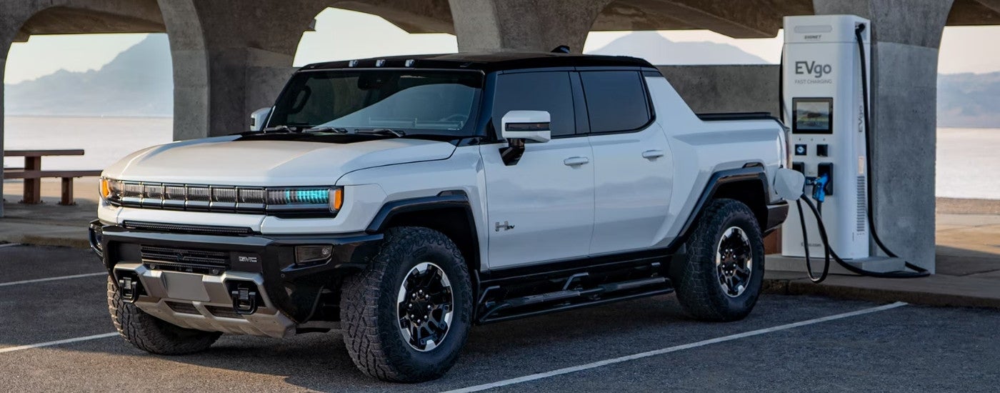 A white 2025 GMC Hummer EV is shown charging.