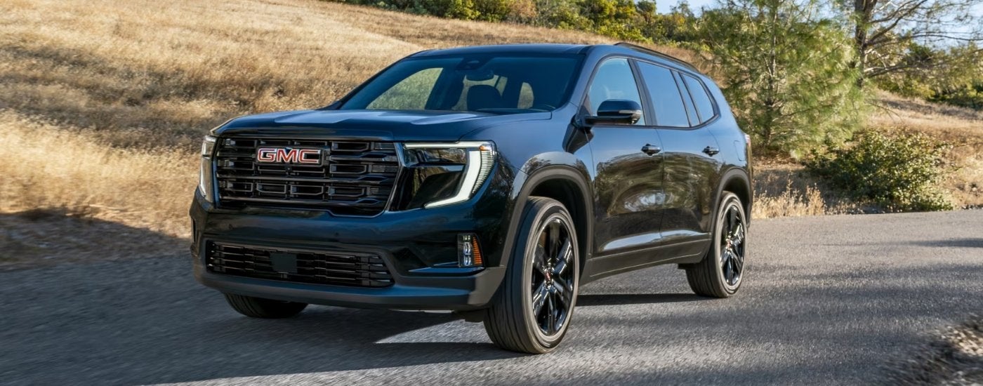 A black 2025 GMC Acadia Elevation is driving to a GMC dealer in Rockwall.