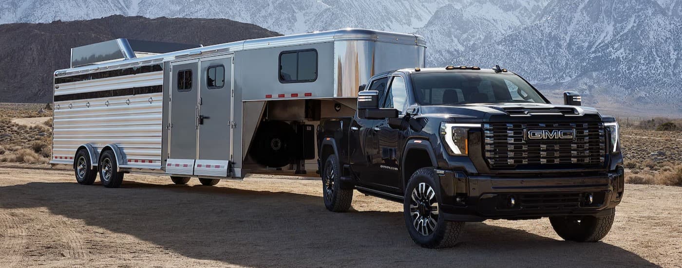 A black 2025 GMC Sierra 2500HD Denali towing a trailer.