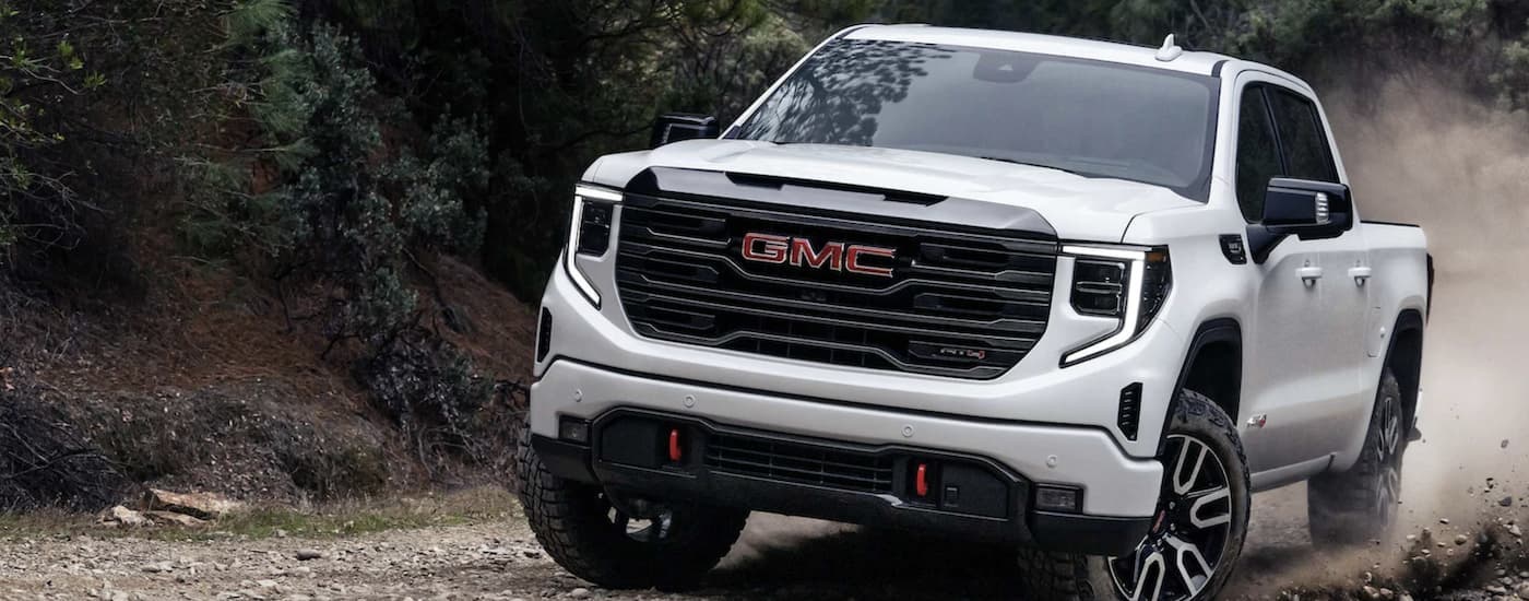A white 2025 GMC Sierra 1500 AT4 off-road on a trail